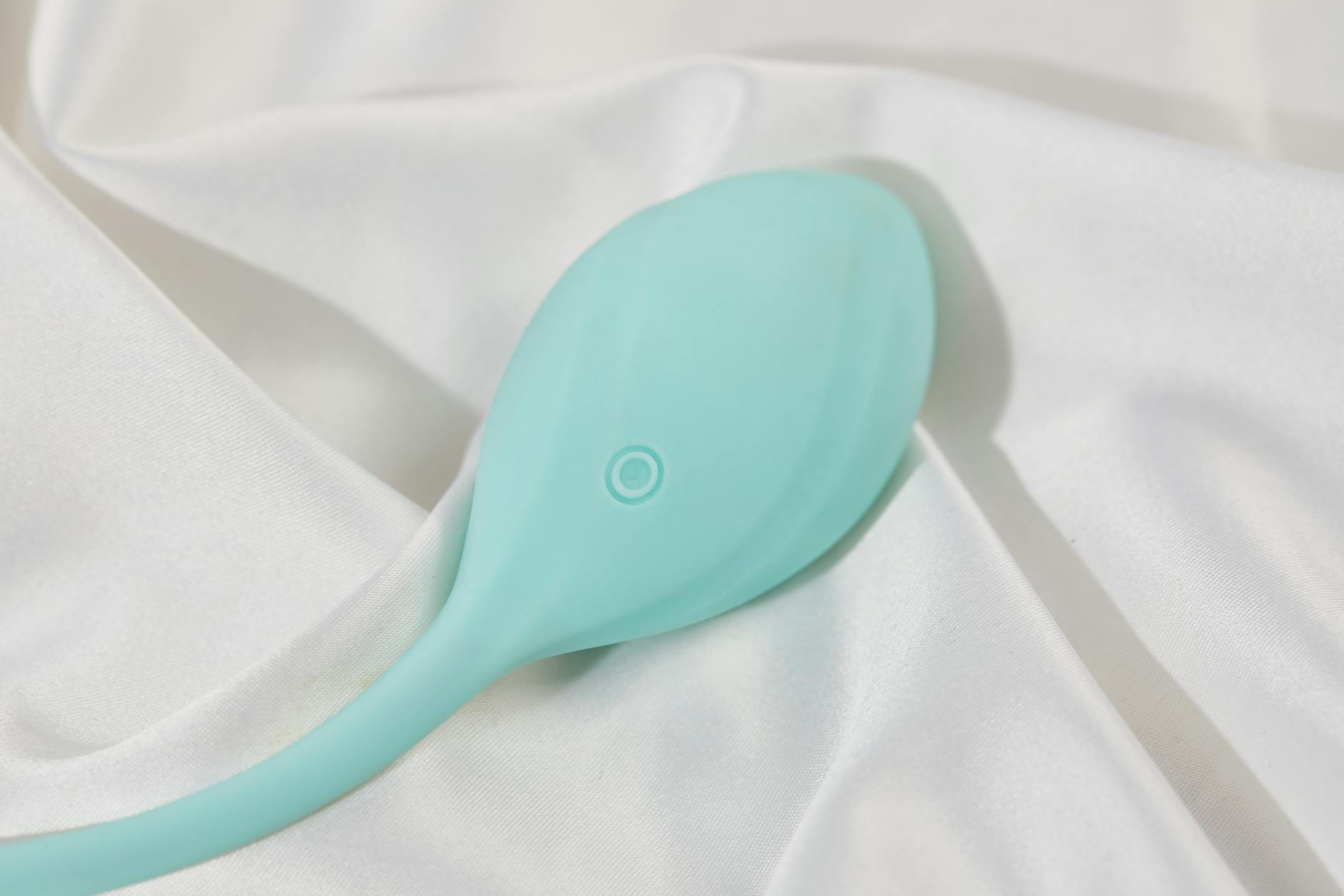 Woman holding blue and pink silicone vibrators, examining different clitoral vibrator options