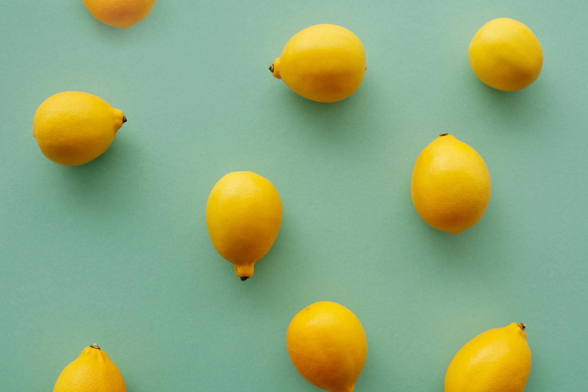 Bright yellow lemons arranged on a pastel green background, symbolizing the lemon clitoral vibrator