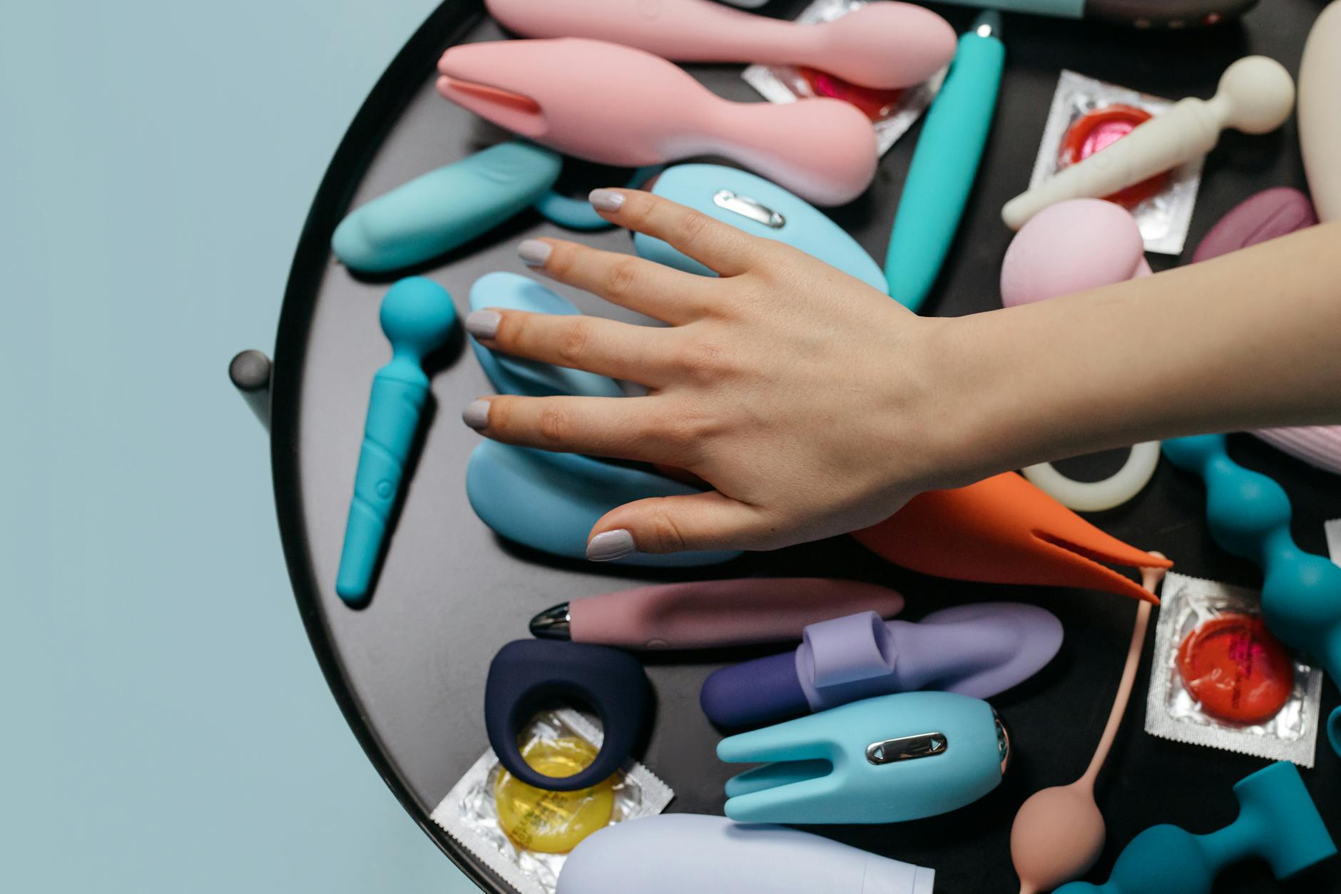 A woman holding two colorful vibrators, representing options for managing sensitivity changes.