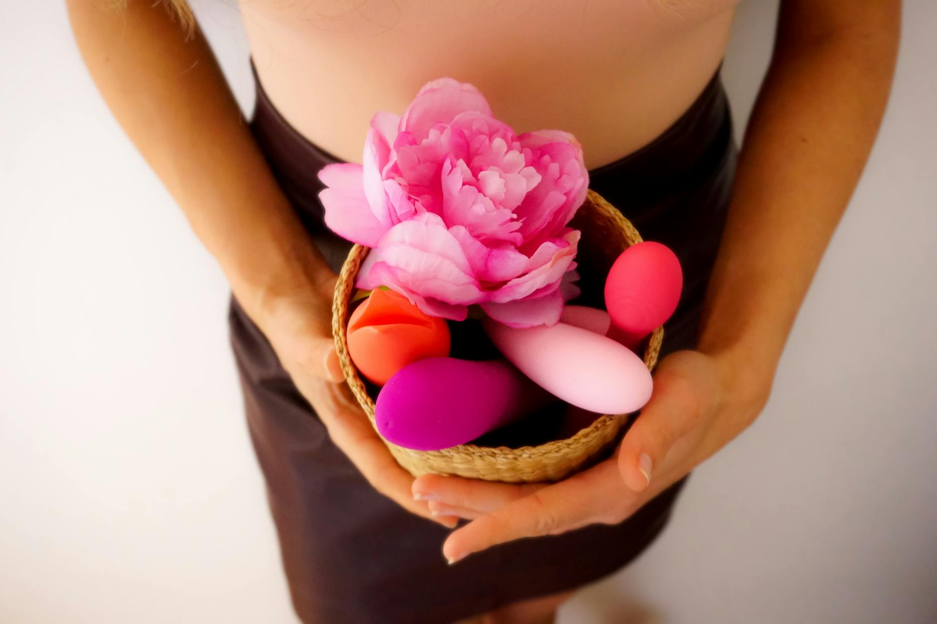 Hands holding pastel-colored silicone vibrators in intimate close-up